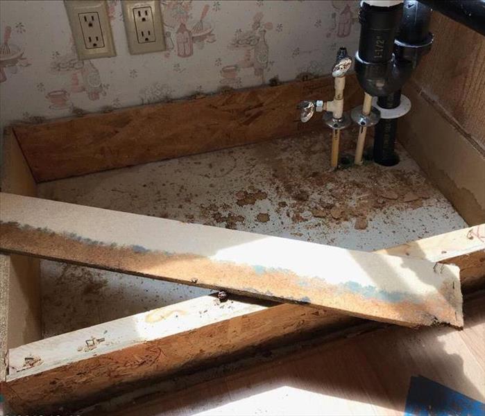 Boards being removed from under a sink due to water damage