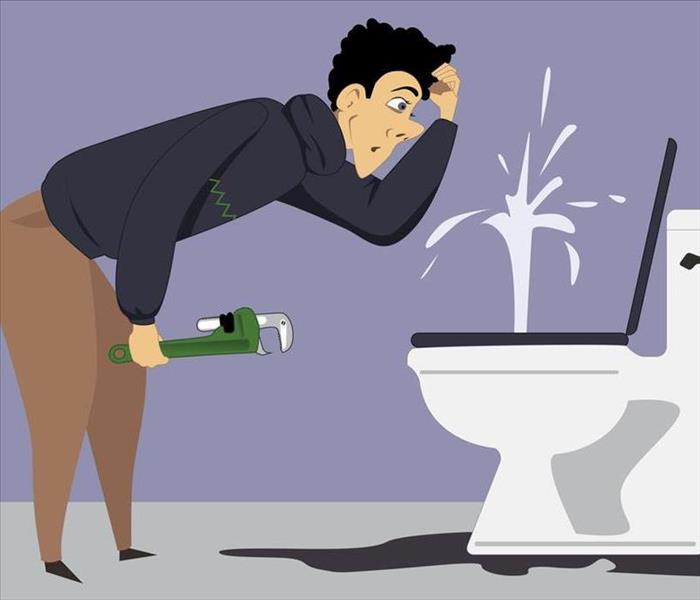 Puzzled man with a wrench looking at a broken toilet