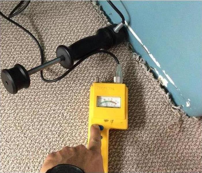 A technician checking with a device the moisture of a home.