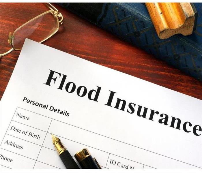 Flood insurance form on a table with a book.